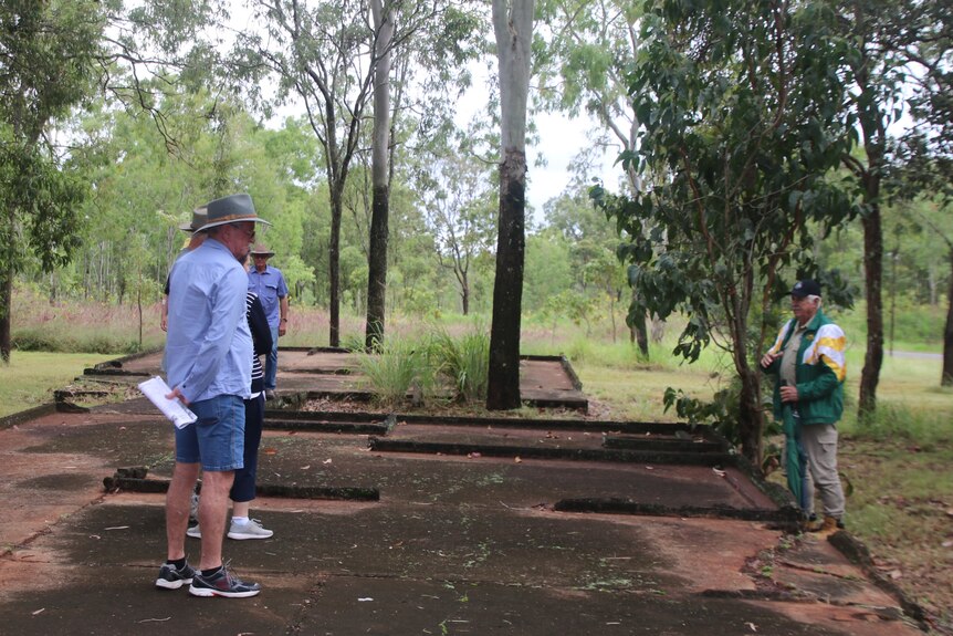 People listening to a lecture on a concrete slab in the bush which is the ruins of the old military hospital  