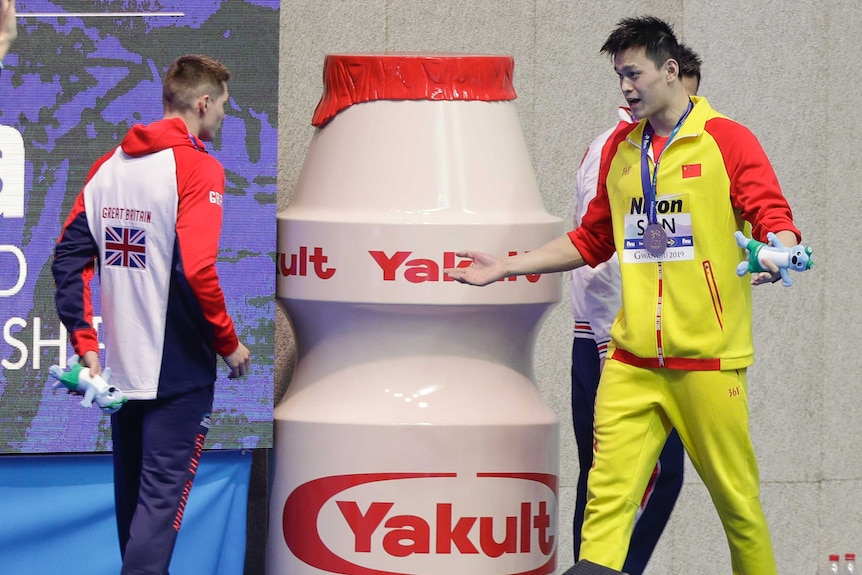 Sun Yang gestures towards Duncan Scott, raising his eyebrows and pouting while throwing a hand up.