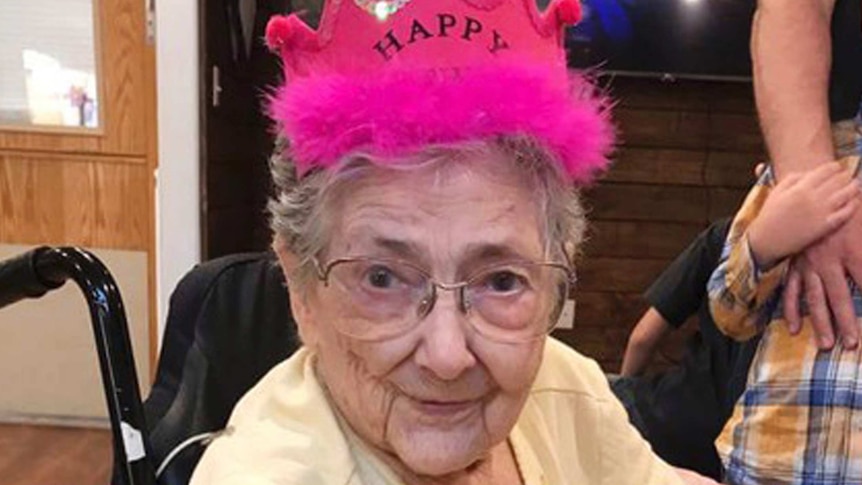 Rose Bentley wears a yellow t-shirt and a pink party crown and sits in a wheelchair looking at the camera