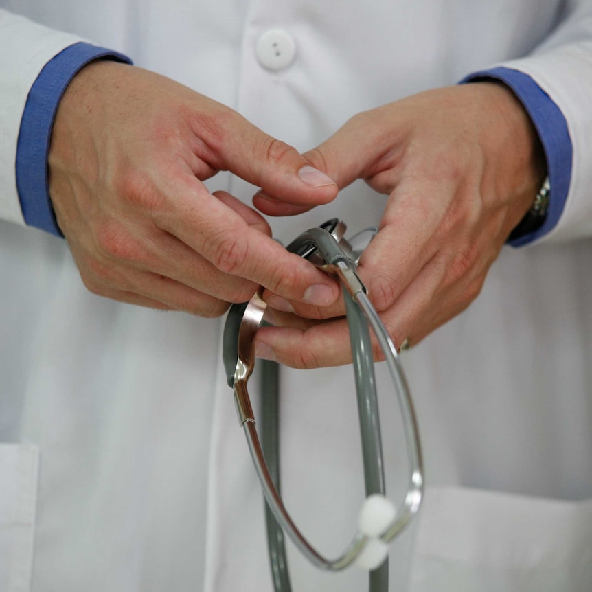 A doctor holds a stethoscope in two clasped hands