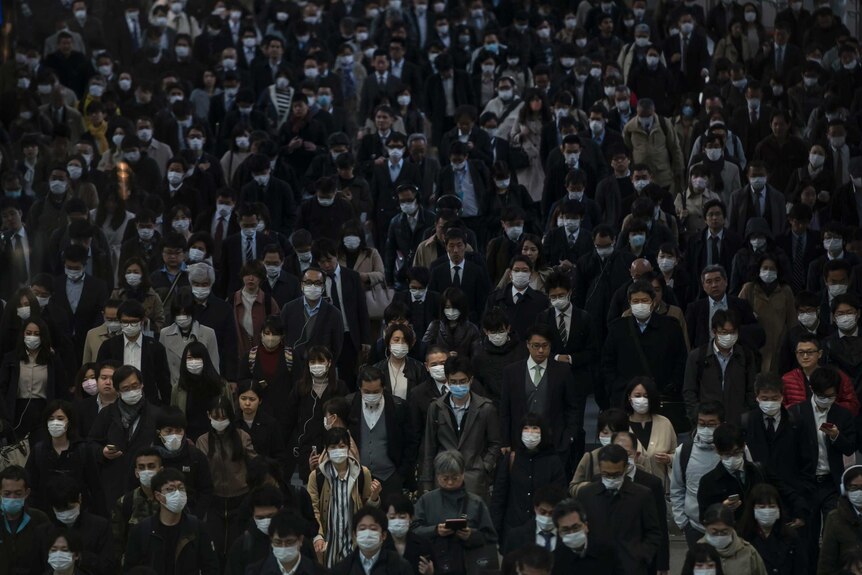 A crowd of commuters wearing face masks