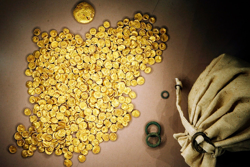 A large pile of gold coins next to a sack