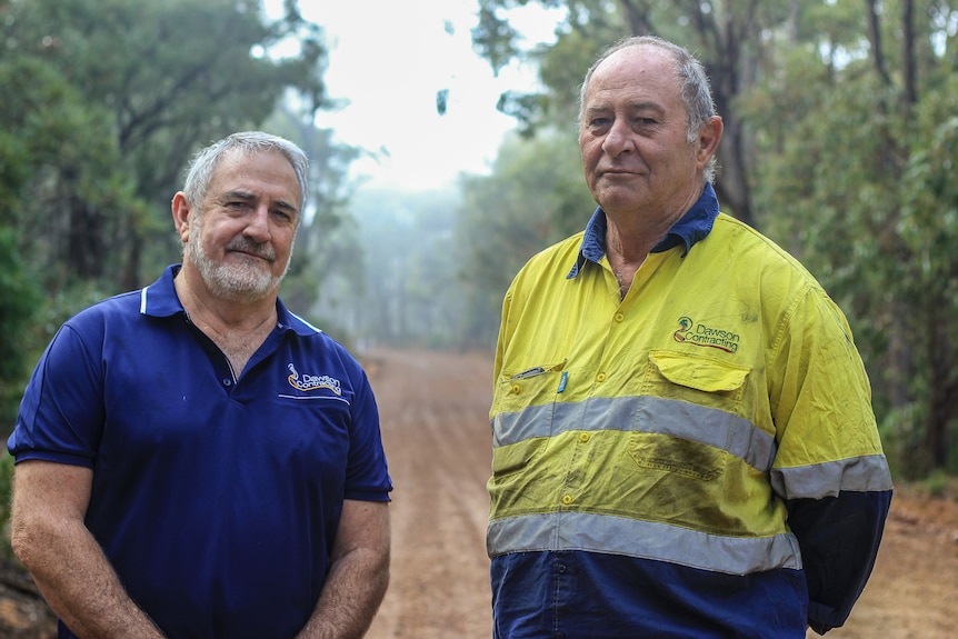 Bernie Dawson on the left in blue polo and Daryl Dawson on right in high vis on dirt road in misty forest.