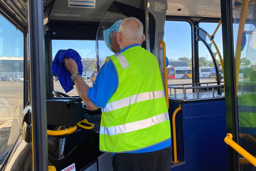 A man cleans the driver compartment of a bus