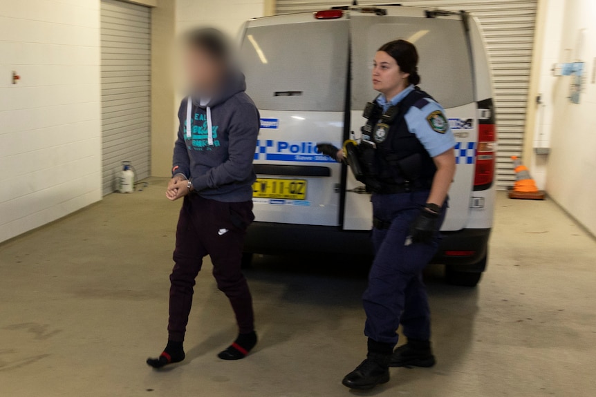 A man and a woman with a police car behind them. 