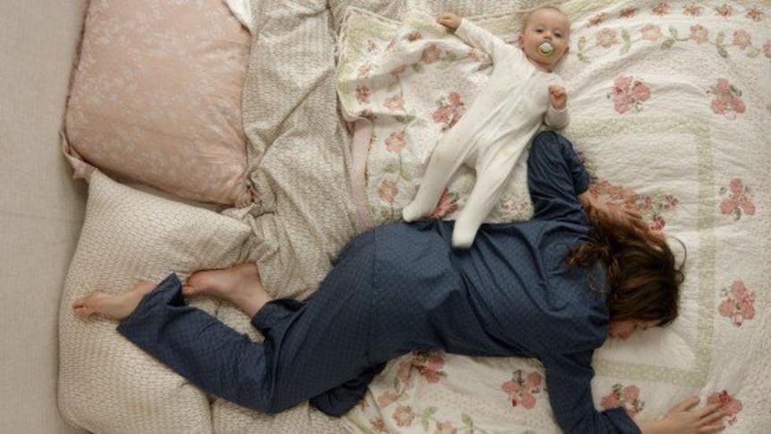 A still image from the ABC comedy show The Letdown, showing actor Alison Bell lying on the bed next to a baby.