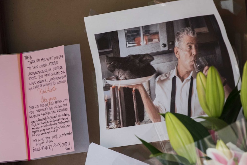 A pink condolences card sits next to a photo of Anthony Bourdain.