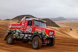 Ales Loprais's red and black truck drives through the desert during the Dakar Rally.