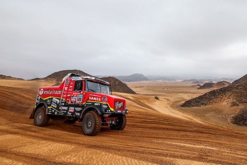 Ales Loprais's red and black truck drives through the desert during the Dakar Rally.