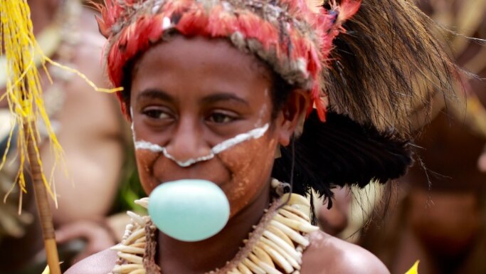 A young girl in traditional costume blowing bubblegum at the 2016 Goroka Show