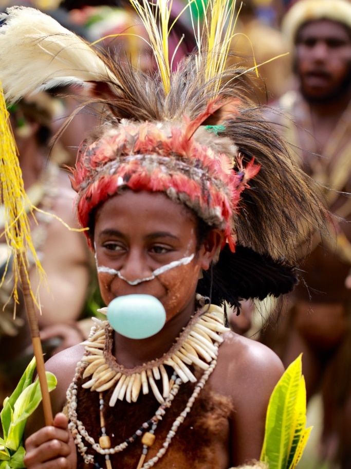 A young girl in traditional costume blowing bubblegum at the 2016 Goroka Show