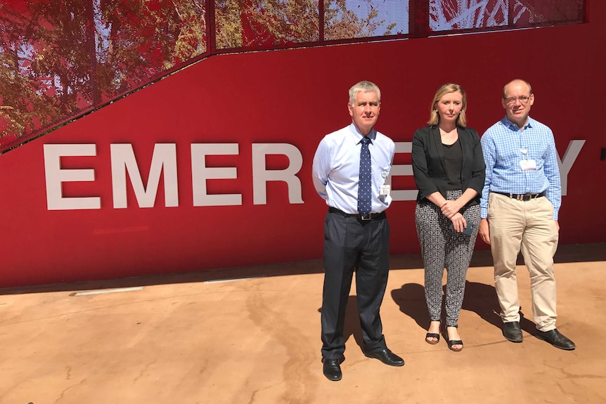 Dr Charles Pain, Emma Reid, and Dr Brian Spain outside the Emergency sign at Royal Darwin Hospital