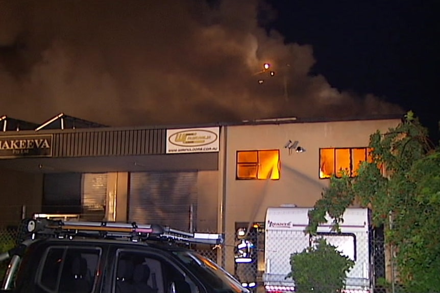 Firefighter sprays water into window of a business on fire in Hemmant