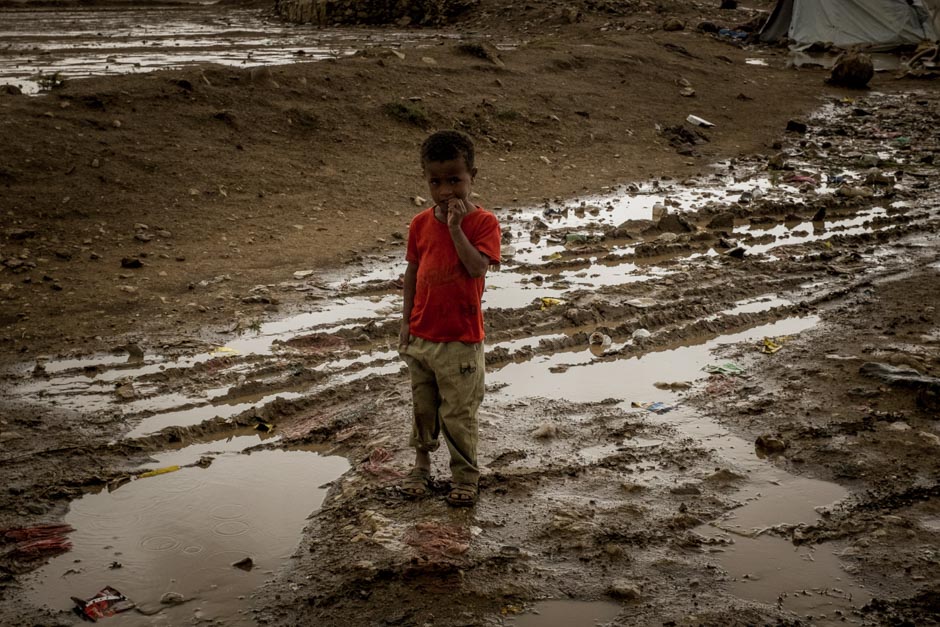 A child stands in mud.