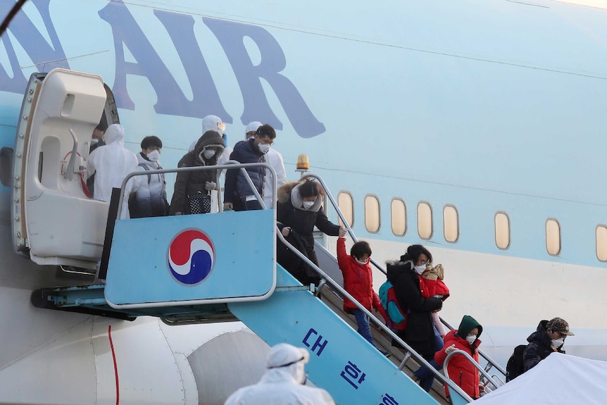South Koreans evacuated from Wuhan, China, disembark from a chartered flight wearing face masks.