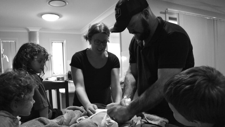 The Twidale family dresses newborn Memphis on the kitchen table.