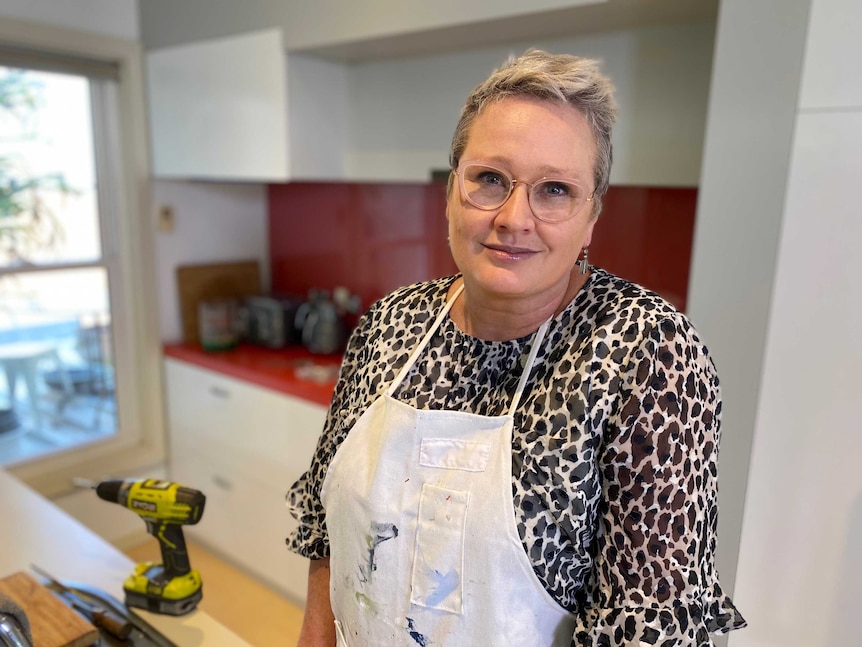 Kate Wild wearing an apron stands in her kitchen next to a drill.