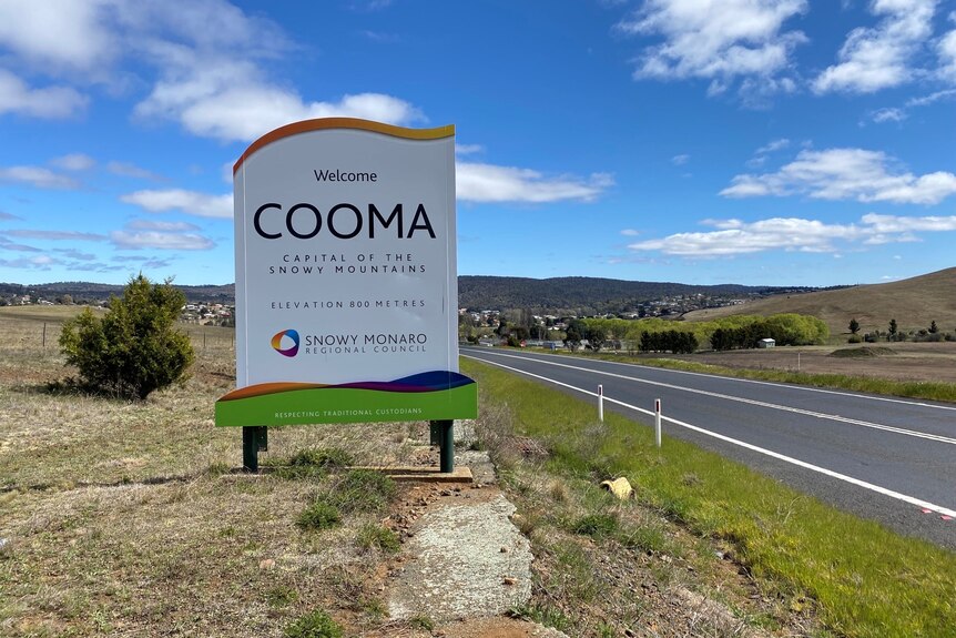 a sign of cooma next to a road