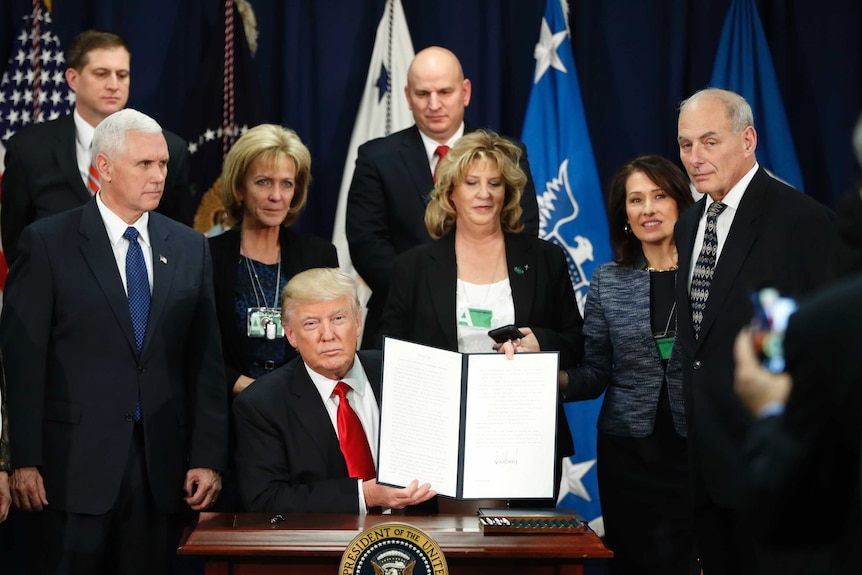 President Donald Trump, with Vice President Mike Pence, holds up an executive order on the Mexico border wall, January 25, 2017.