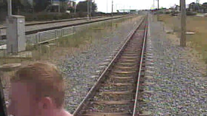 An image of a redheaded man with train tracks stretching out to the background.