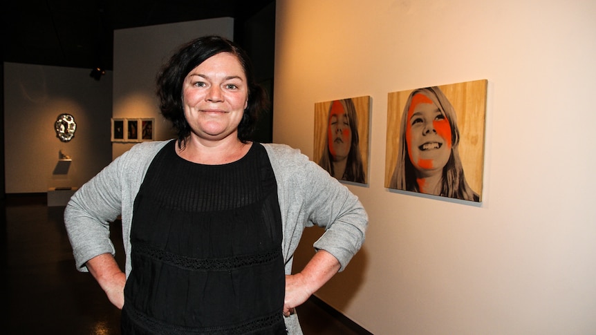Mici Boxell in the foreground with two of her works, depicting her daughter in the background.
