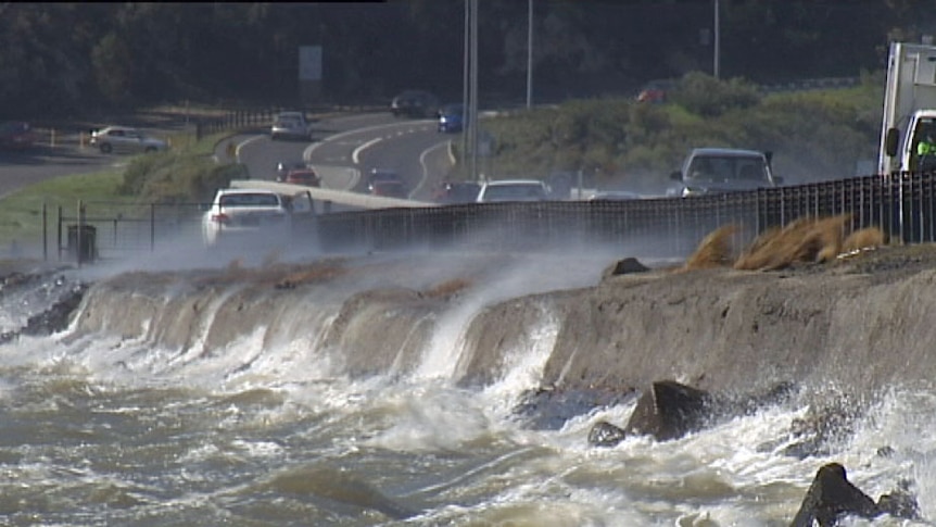 Water washes up on the Midway Point causeway after strong winds buffet Tasmania