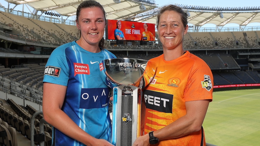 Tahlia McGrath and Sophie Devine smile while holding the WBBL trophy inside Perth Stadium