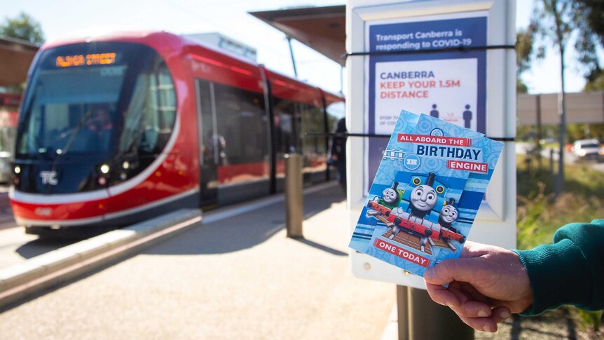 Canberra light rail arrives to a deserted platform with a COVID-19 warning poster in place.