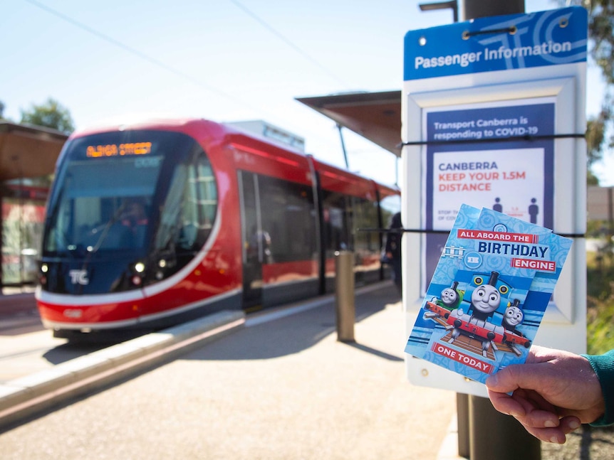 Canberra light rail arrives to a deserted platform with a COVID-19 warning poster in place.