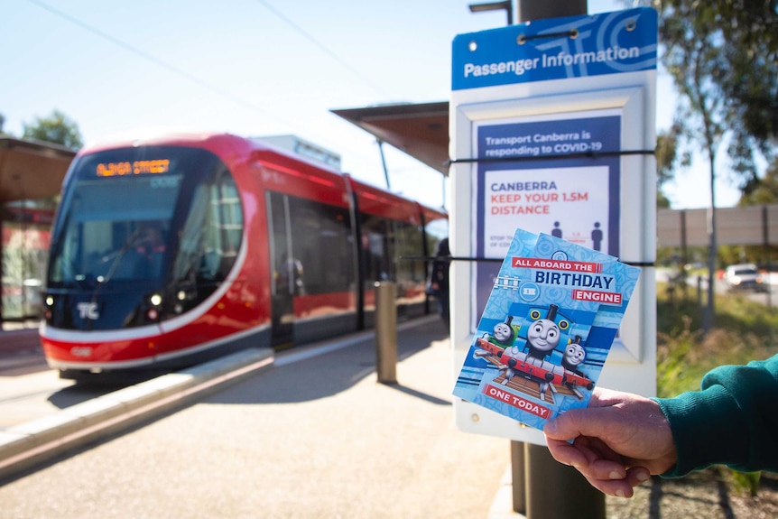 Canberra light rail arrives to a deserted platform with a COVID-19 warning poster in place.