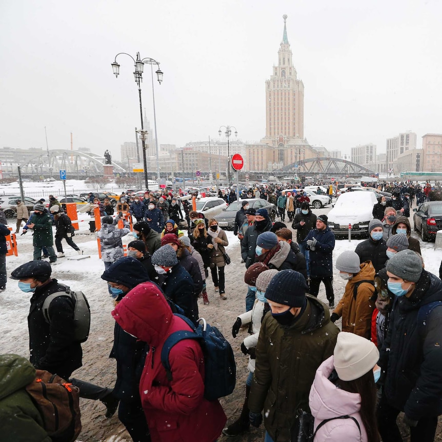 A large number of people walk on a street in snowy weather during a protest in Moscow, Russia.