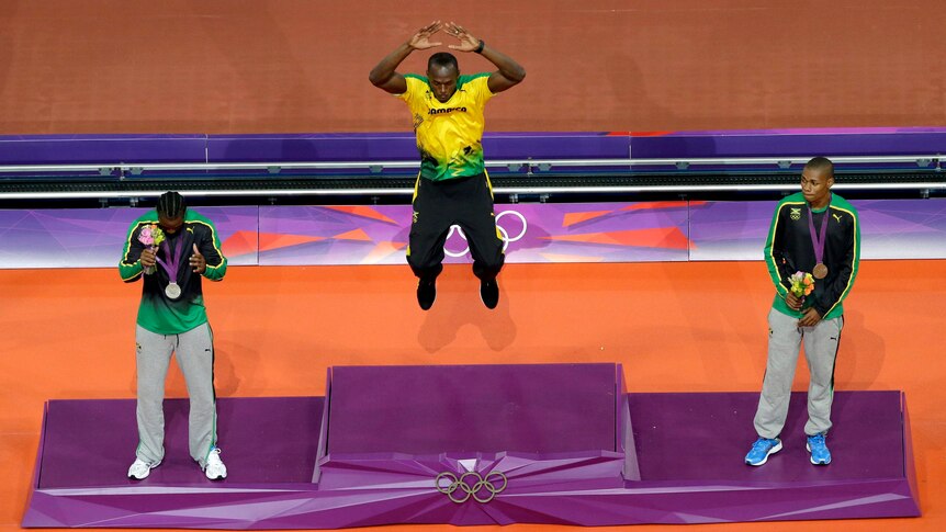 Usain Bolt jumps on the podium to accept his gold medal for winning the 200m.