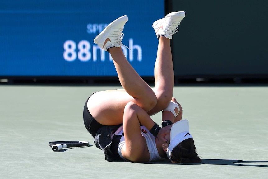 Bianca Andreescu tumbles to the court floor after winning the Indian Wells women's tennis final
