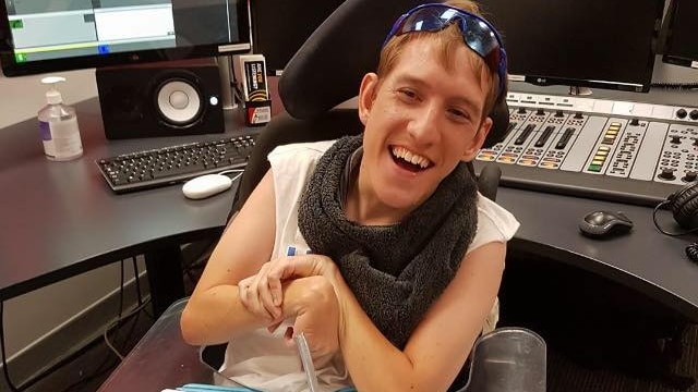 A man smiling sitting at a radio production desk