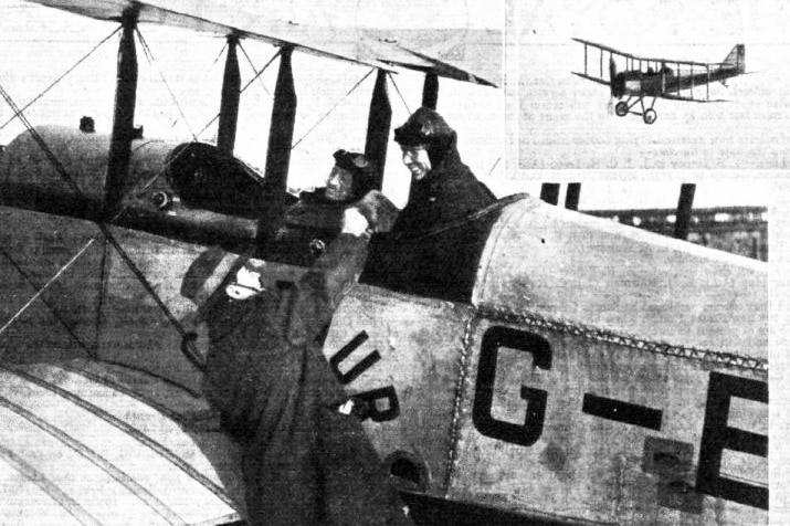 A black-and-white image of a man shaking the hand of a pilot in a biplane.
