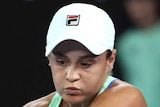 A female tennis player plays a doubled-handed backhand as she watches the ball at the Australian Open.