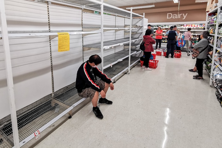 People waiting in the toilet paper aisle for a delivery of toilet paper, paper towel and pasta at Coles Supermarket.