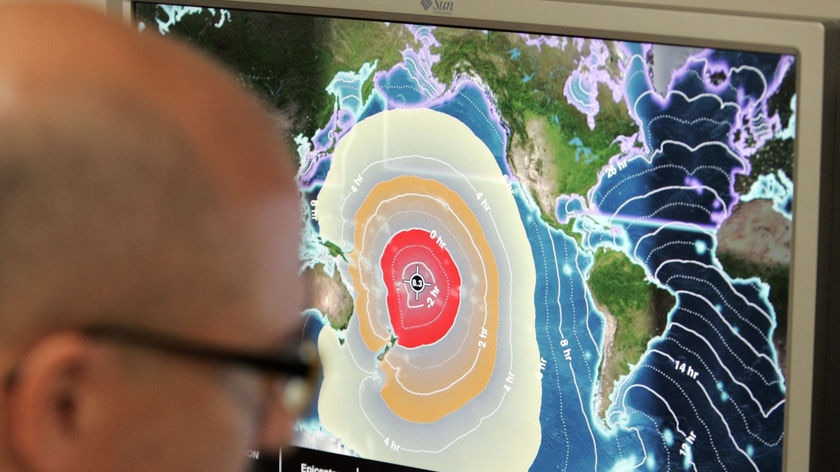 A meteorologist looks at maps of tsunami warnings