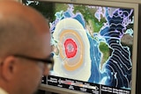 A meteorologist looks at maps of tsunami warnings