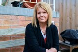 A middle-aged woman sits on a bench