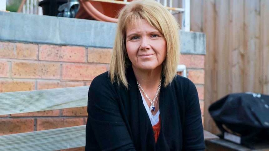 A middle-aged woman sits on a bench