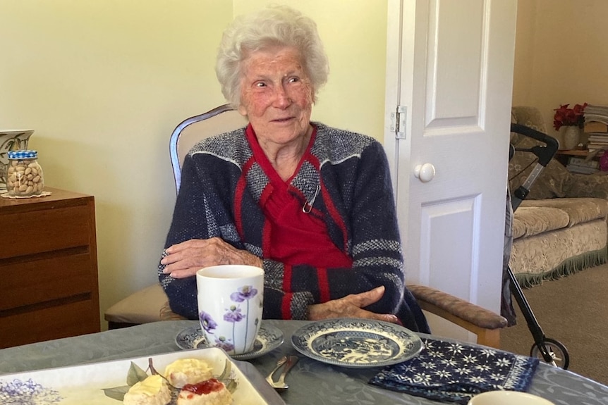 An elderly woman sitting at her dining table.