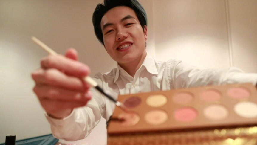 Xu Xiong holding up a colour palette during a make up tutorial