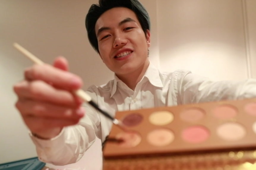 Xu Xiong holding up a colour palette during a make up tutorial