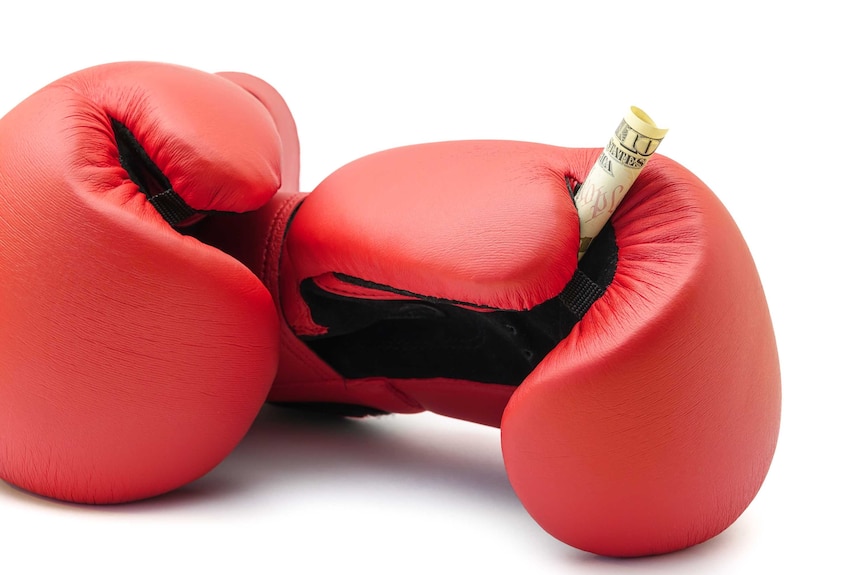 A red pair of boxing gloves and a rolled up US dollar bill.