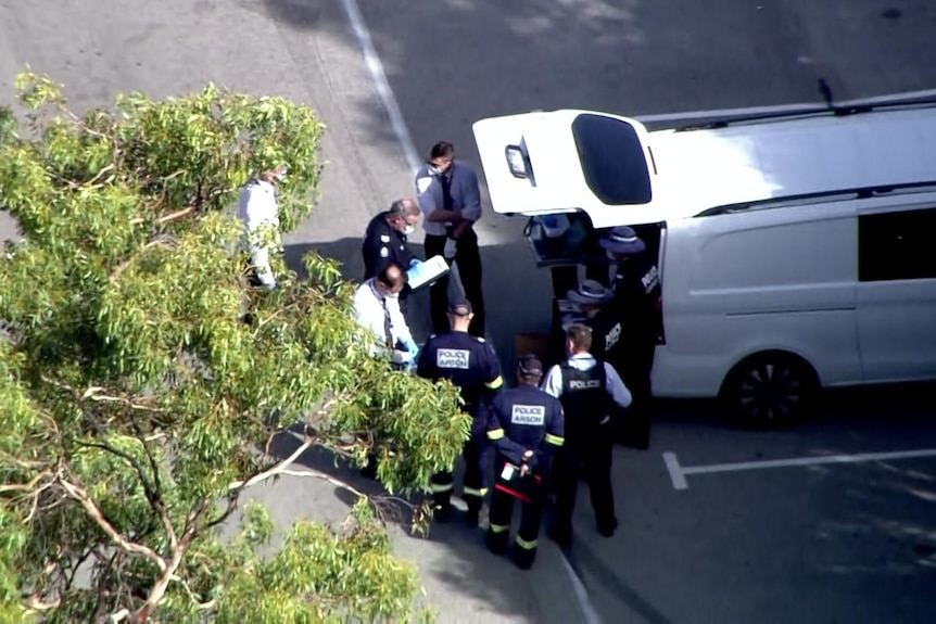An aerial image of a group of police investigators huddling in a car park.