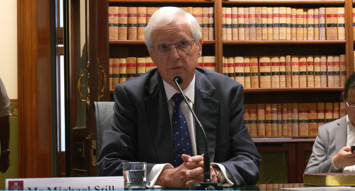 El hombre se sienta allí y habla por un micrófono.