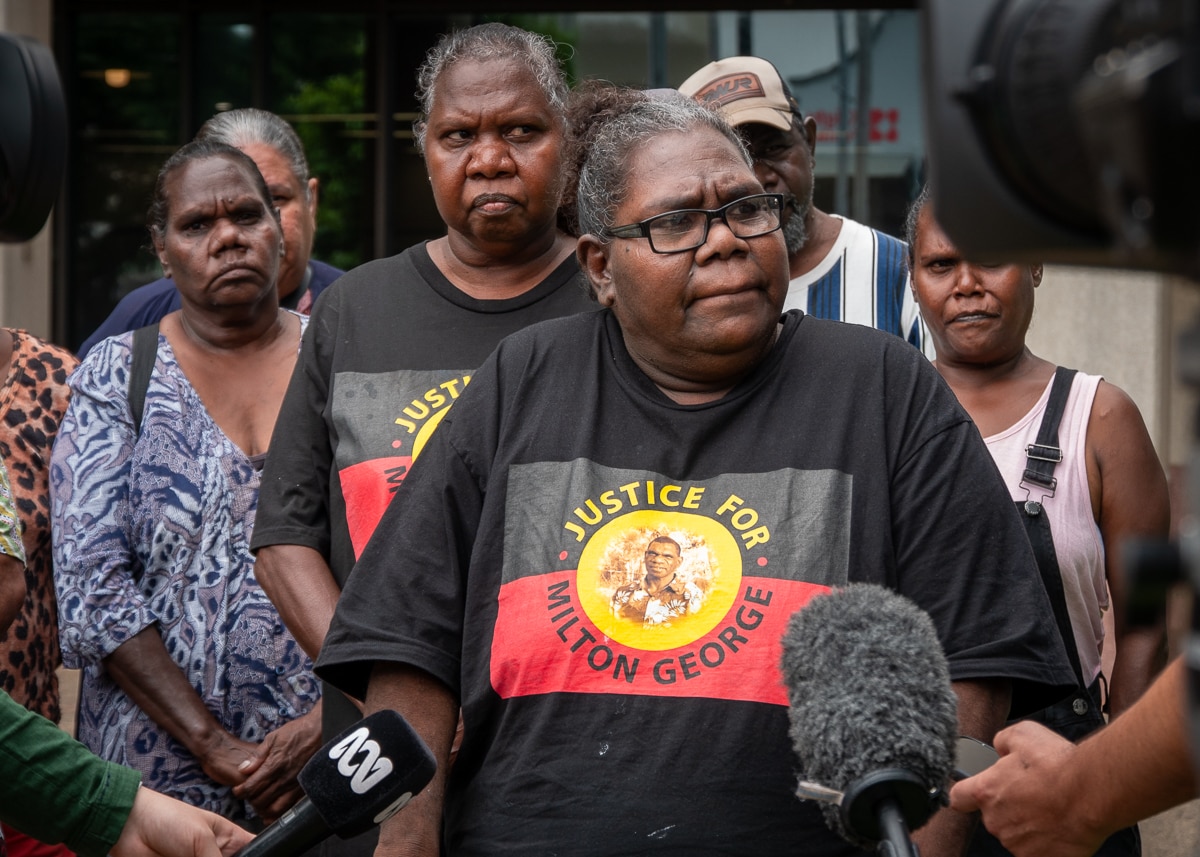 Aboriginal woman talking to reporters flanked by family