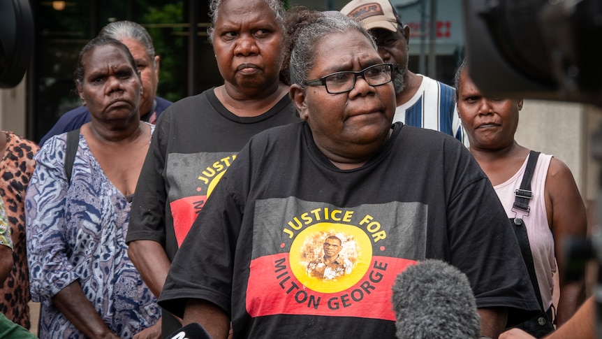 Aboriginal woman talking to reporters flanked by family