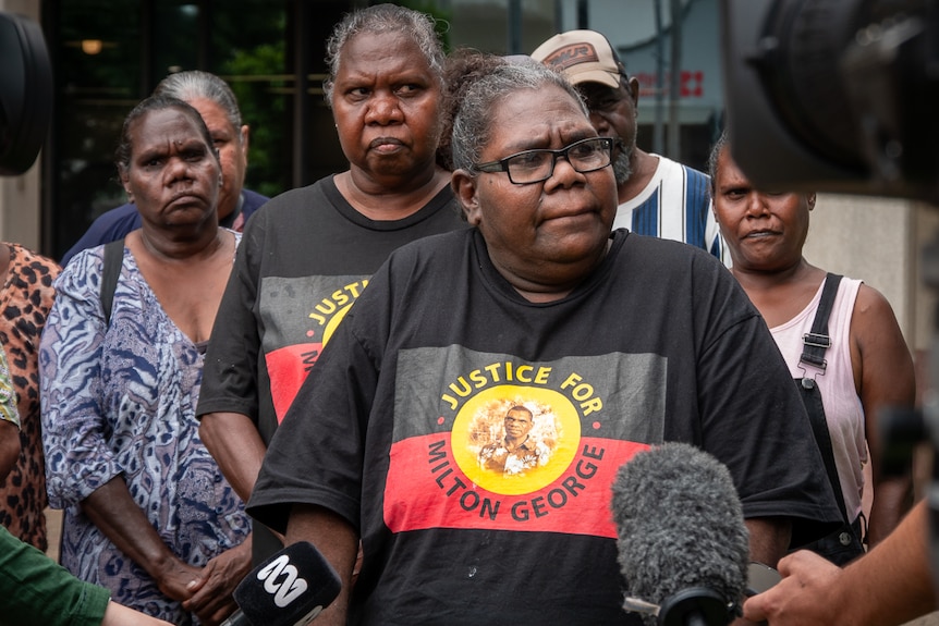 Aboriginal woman talking to reporters flanked by family